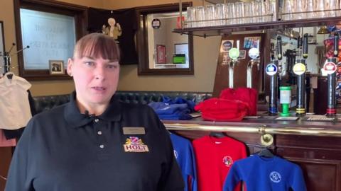 Landlady in pub offering school uniforms