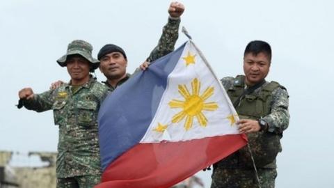 Philippine soldiers aboard their armored personnel carrier celebrate after President Rodrigo Duterte declared Marawi City "liberated", inside the battle area of Bangolo in Marawi on October 17, 2017.