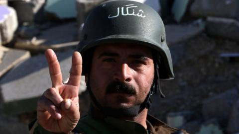 A Kurdish fighter flashes the victory sign in the northern Iraqi town of Sinjar, in the Nineveh Province, on 13 November 2015