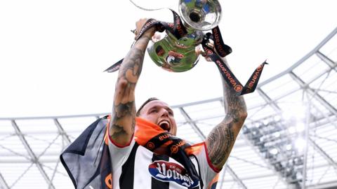 Jordan Maguire-Drew holds the National League play-off final trophy aloft