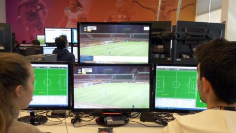 Two Opta data analysts look at a number of computer screens showing football footage and data