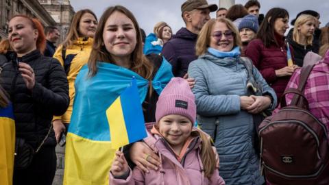 People drink sparking wine, waves flags and sing songs as they celebrate the liberation of part of the city of Kherson in Independence Square on November 12, 2022 in Kyiv