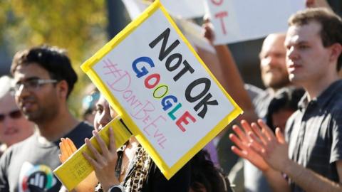 A Google employee (centre) holds a sign that reads "Not OK Google" during a walkout in Mountain View, California