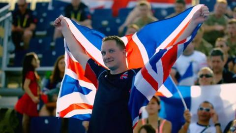 A competitor during one of the Invictus Games holds the Union Jack