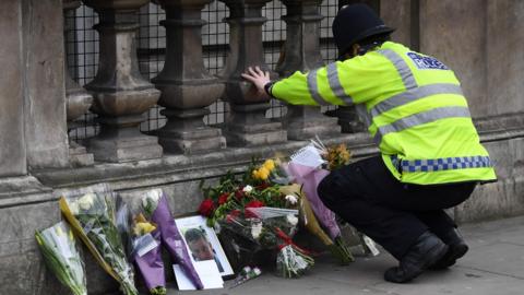 A policeman laying flowers in tribute to PC Keith Palmer