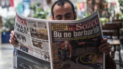 A man reads a newspaper with a headline concerning diplomatic tensions between Turkey and The Netherlands, which translates as "What a Barbarism" in Istanbul on March 13, 2017.