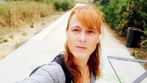 A photograph of Magg Biskupski taken from her Facebook profile shows her standing upon a sunlit country road