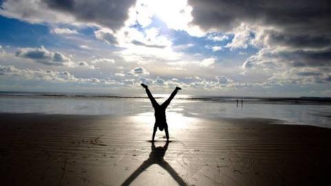 silhouette of someone handstanding on the beach