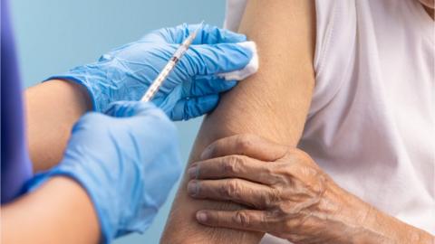 Nurse vaccinating an older woman