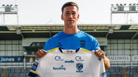 Wes Bruins holds a Warrington shirt for his signing photo