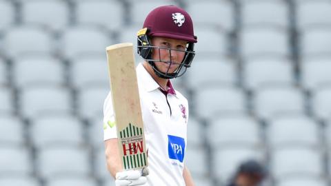 Somerset batter James Rew holds up his bat after hitting a century against Lancashire