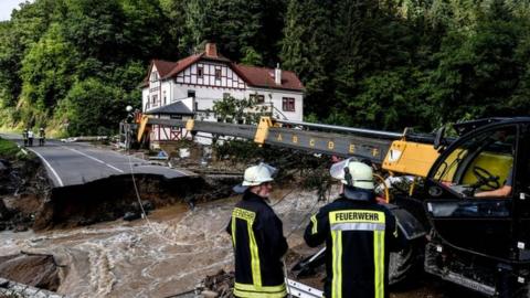 Firefighters next to a damaged road after flooding in Schuld, Germany