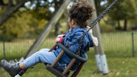 Young girl on swing in play park (stock image)