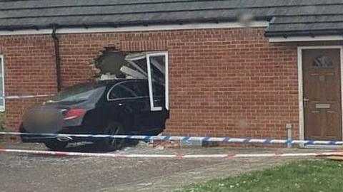 Car half inside a bungalow