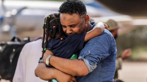 A father hugs his daughter before they are evacuated from Sudan