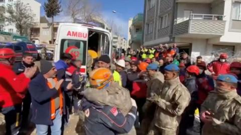 Dozens of rescue workers stand around an ambulance in Turkey