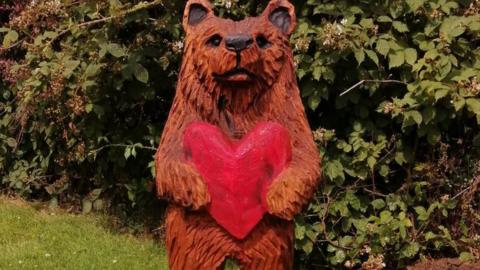 A statue of a bear holding a red heart