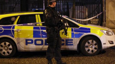 Armed police officer and police car