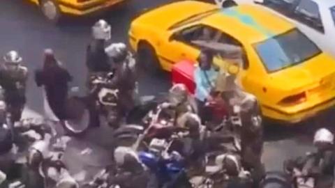 Still from a video showing woman fleeing police in Iran
