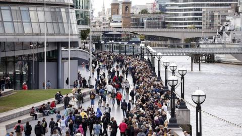 People queue on The Queen"s Walk along the River Thames as they wait to pay their respects to Britain"s late Queen Elizabeth II lying in state at Westminster Hall, in London