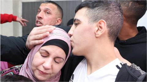 A boy, Ahmen Salayme, kisses his mother