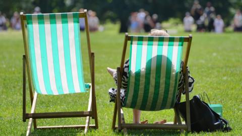 Two deck chairs sitting in a park in sunny weather