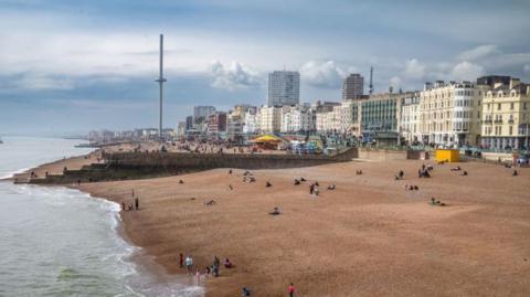 A view over Brighton seafront. There is a pebbled beach and buildings in the background. 