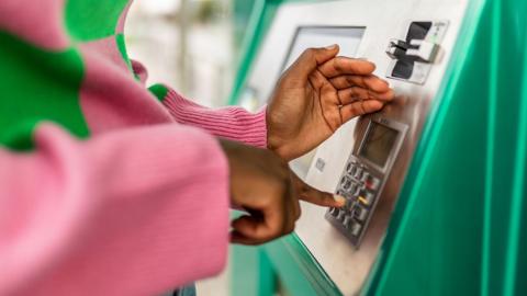Close-up of a young woman's hands using a cash machine