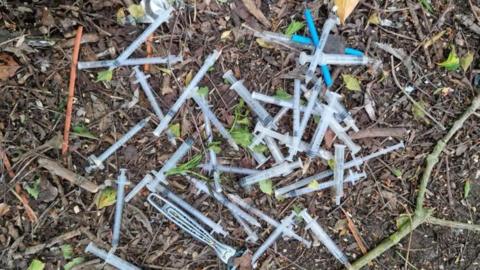 Discarded plastic syringes lying on the ground.