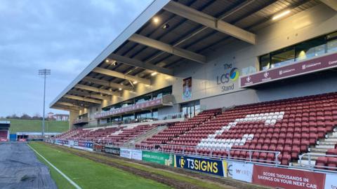 A two-storey stand in a football stadium. The first level has claret and white seats while the second level has two glass pitch-facing boxes. 