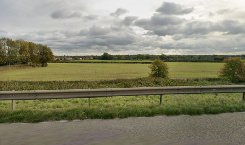 Fields and trees behind a motorway barrier