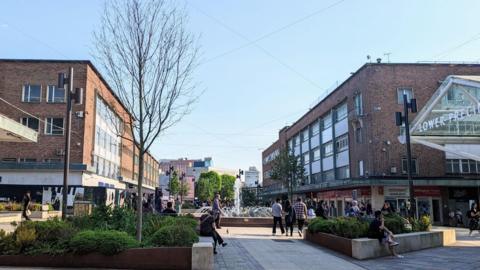 The centre of Coventry, showing the shops either side of the centre, with green bushes.