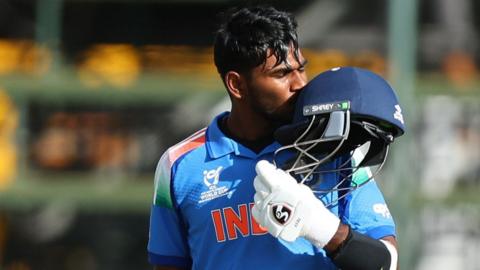 Aaron George celebrates his century by kissing his helmet