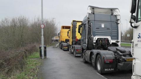 Lorries parked in a lay-by, with a bin to the left-hand side.