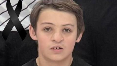 An image of Alfie Hallett who is wearing a black basketball uniform and is looking directly at the camera