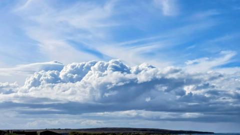 Grey thunder clouds building on the horizon with headland beneath
