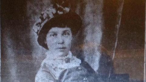 A black and white, very grainy portrait of Lucy Sands. She is wearing a hat and Victorian clothing, including a white lace collar. 