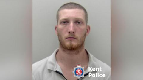 A man with a stern expression in a police mugshot.