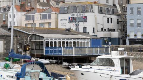 A picture of the former restaurant at the Victoria (Crown) Pier in Guernsey. The building is empty with a glass conservatory overlooking the harbour. There are 