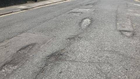 A road with five potholes in shot