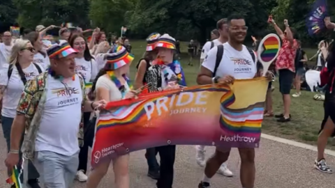 Part of Windsor's Pride parade four people carrying a 'Pride journey' banner and a crowd in white T-shirts follows behind