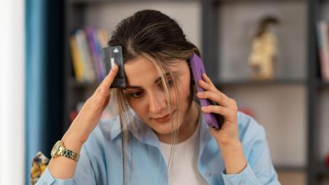 Young woman on the phone with a debit or credit card in the other hand.