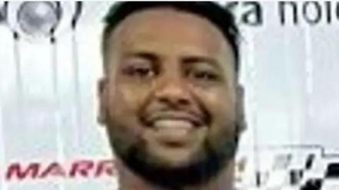A photograph of murder victim Abdullah Hassan. He has short, dark hair and a beard
