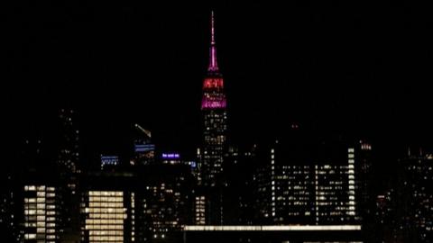 The Empire State building glows pink as part of the New York City skyline.