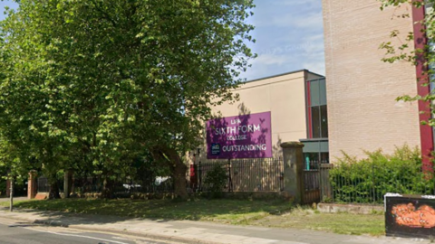 A large purple sign on the side of a building behind iron railings reads 'LIPA sixth form college outstanding'