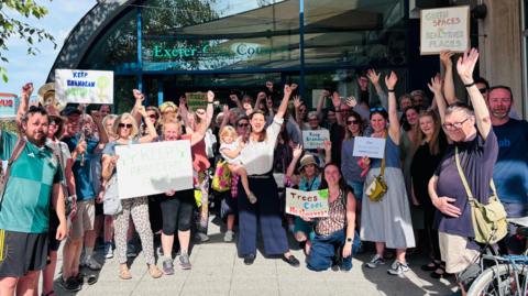 A group of people outside Exeter City Council offices, some with placards