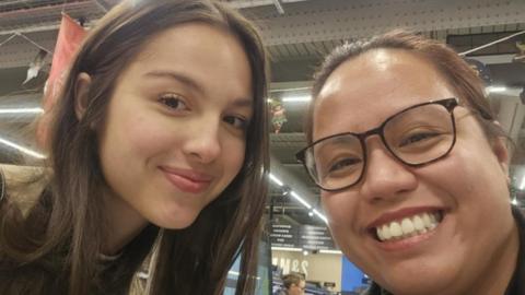 US pop star Olivia Rodrigo takes a selfie with a Llandudno resident. Olivia Rodrigo is on the left and is smiling. Rose is on the right is smiling and is wearing brown framed glasses.