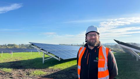 James Clifford of Harvest Green Developments Ltd stood in front of solar panels at the former Hempstead landfill site.