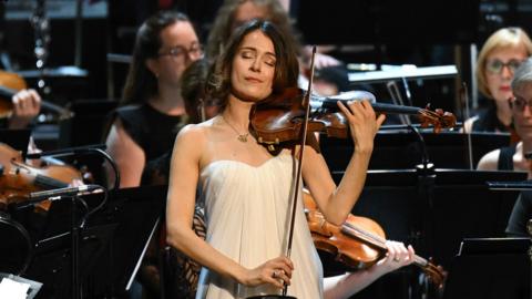 A violinist performing with an orchestra.