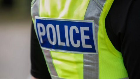 A bright yellow police vest with the words "POLICE" in bold white letters against a blue background.